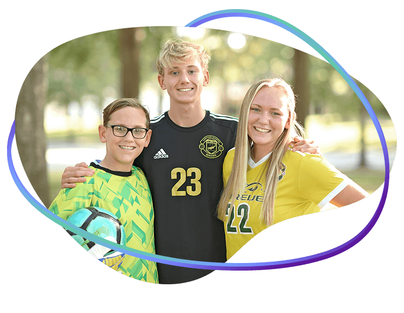 Three smiling teens in soccer jerseys